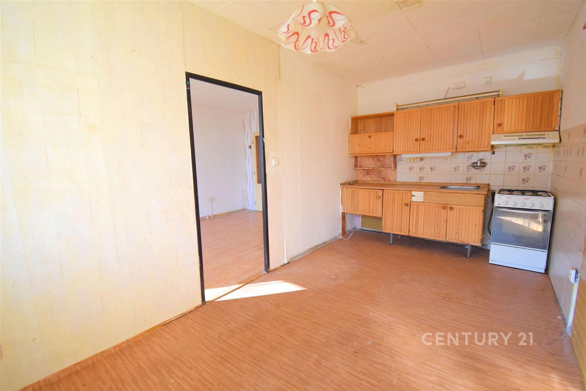 Kuchyň s linoleem, dřevěné skříňky, vestavěné úložné prostory, prostorná a světlá.