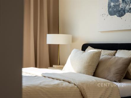 Prostorná ložnice s moderním designem, světlé ložní prádlo a tlumené osvětlení, velká okna zajišťují dostatek denního světla.