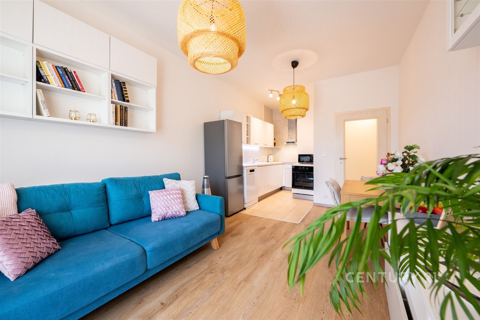 Světlý obývací pokoj s moderní parketovou podlahou, velká okna, stylová závěsná svítidla a vestavěné skříně, útulný a elegantní prostor.