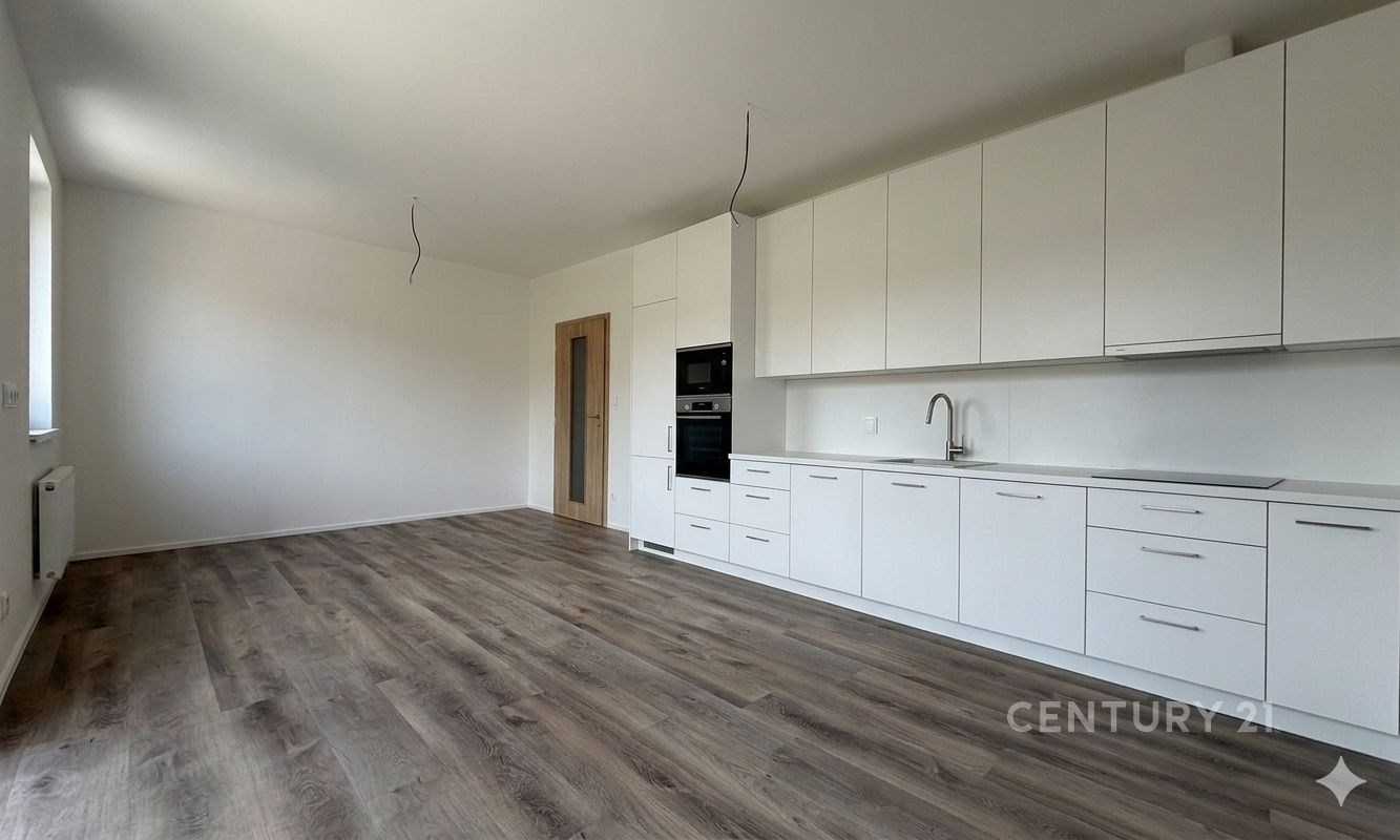 Moderní kuchyň s laminátovou podlahou, vestavěnými spotřebiči a světlými skříňkami, ideální pro otevřený koncept bydlení.