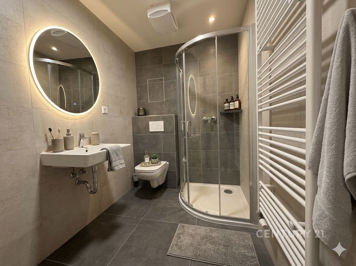 Moderní koupelna s velkoformátovými dlaždicemi, sprchovým koutem a kruhovým zrcadlem, která působí elegantně a svěže.