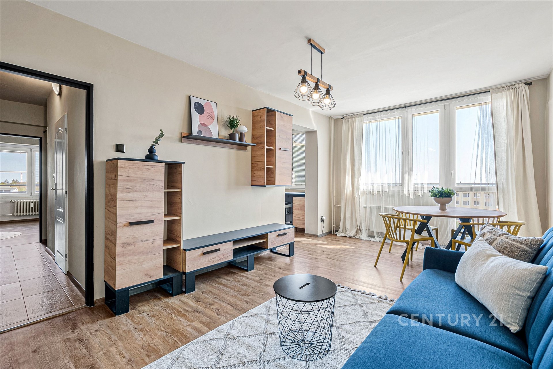 Světlý obývací pokoj s parketovou podlahou, velkými okny a moderním nábytkem. Světlé a vzdušné provedení ideální pro relaxaci.