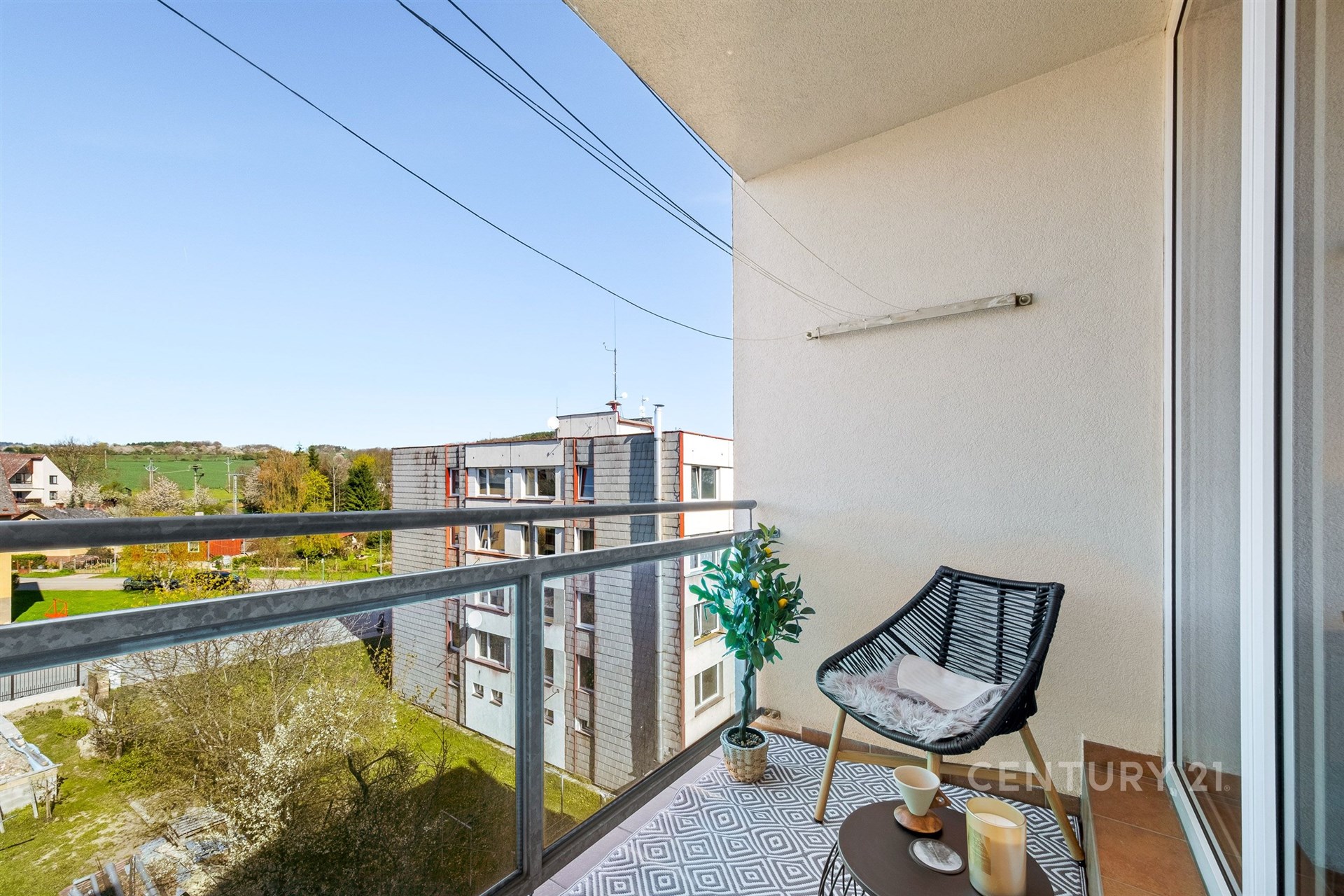 Balkón s moderní keramickou dlažbou, výhledem na okolní zeleň a pohodlným venkovním posezením, vhodný pro relaxaci.