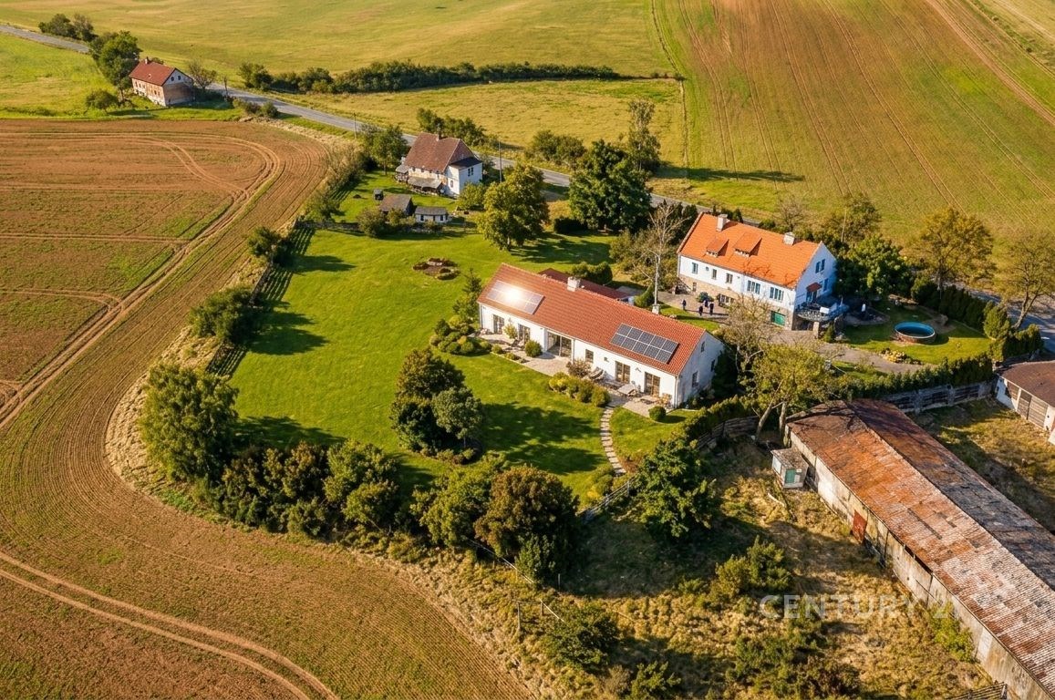 Letecký pohled na rozsáhlou vilu s červenou střechou, okolní velká zahrada, tiché venkovské prostředí, udržovaný trávník, slunná lokalita.