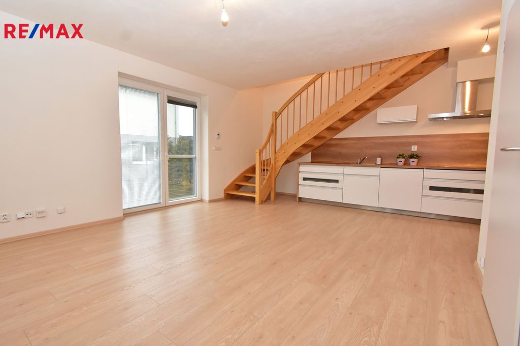 Obývací pokoj s kuchyňským koutem s výhledem a vstupem na terasu a zahradu.