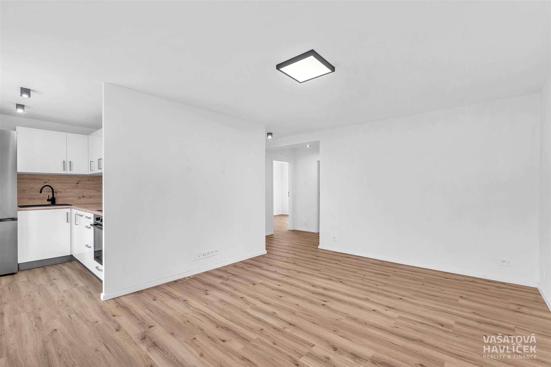 Světlý obývací pokoj s moderní kuchyní, parketová podlaha, vestavěné spotřebiče, svěží bílý dekor, otevřený prostor, ideální pro moderní bydlení