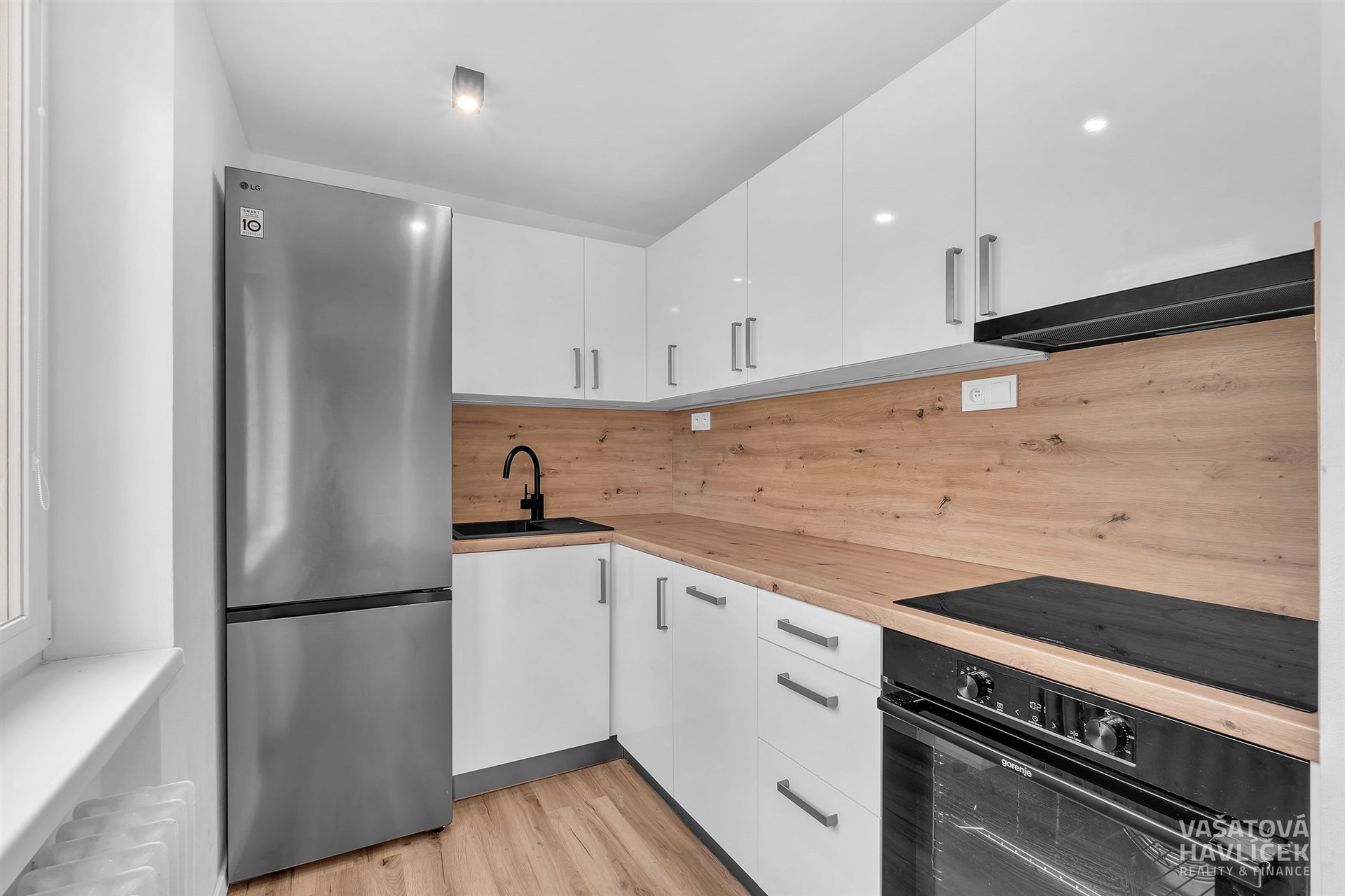 Moderní kuchyň s bílými skříňkami, dřevěnou pracovní deskou, parketová podlaha, vestavěné spotřebiče, světlé provedení