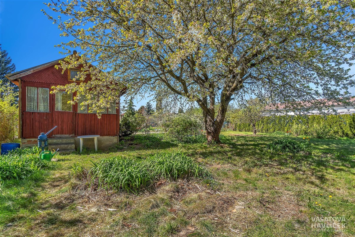 Zahrada s ovocnými stromy a zahradním domkem, oplocená pro soukromí, vhodná k rekreaci. Nachází se na klidném místě, ideální pro rodinné aktivity.
