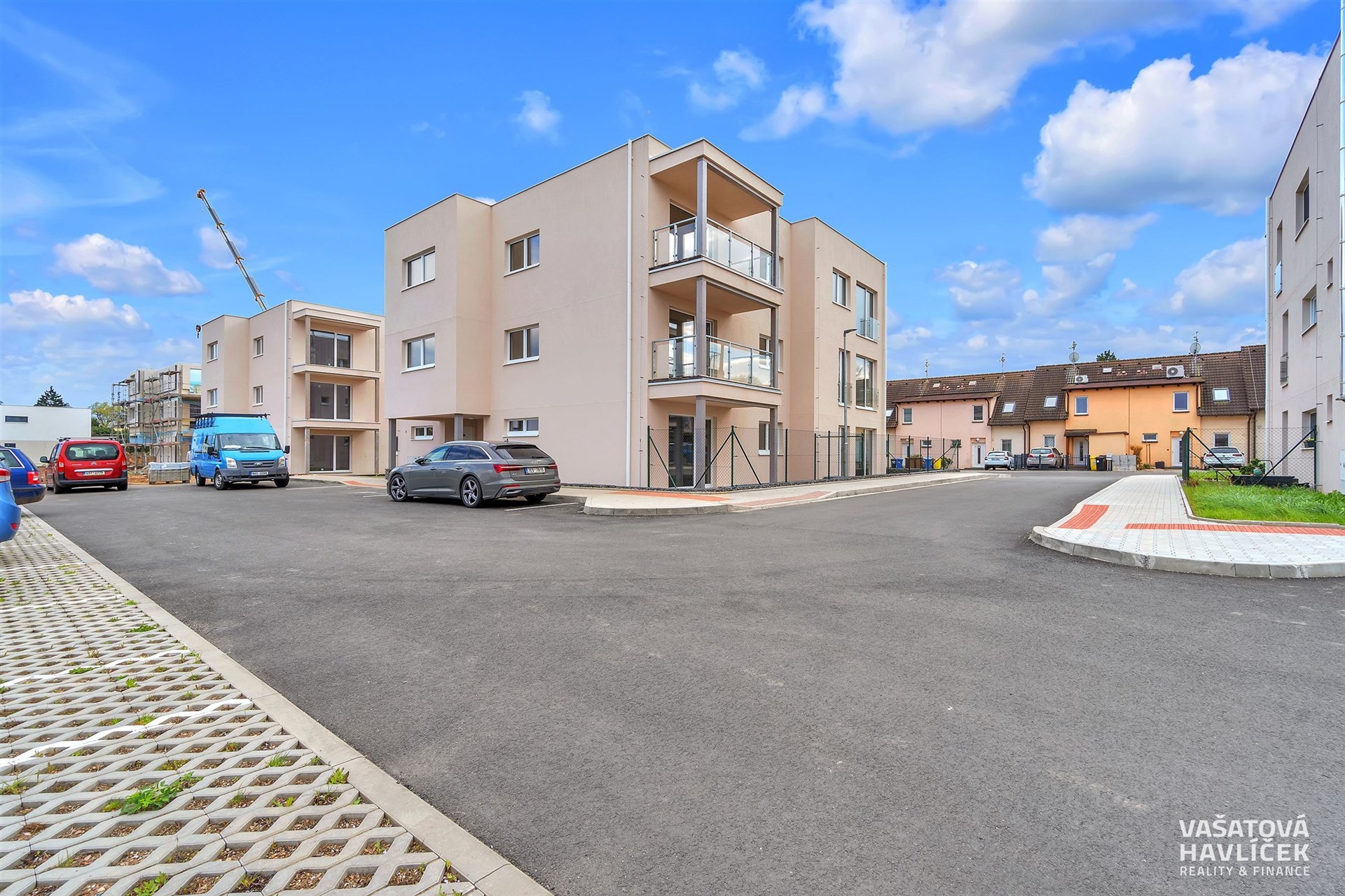 Moderní bytový komplex s balkony, čerstvě dokončený s moderním designem. Parkoviště s dlážděným povrchem poskytuje praktické parkování.