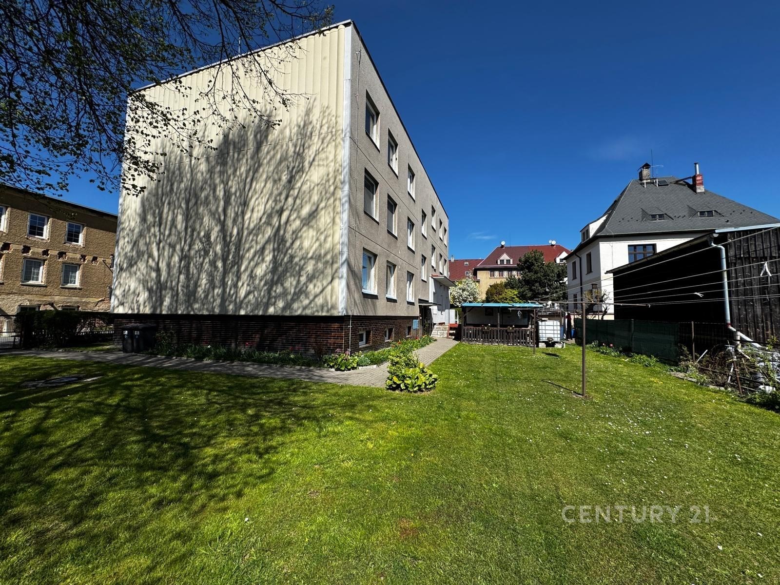 Moderní bytový dům se zahradou, světlá fasáda, klidná lokalita, dobrý stav.