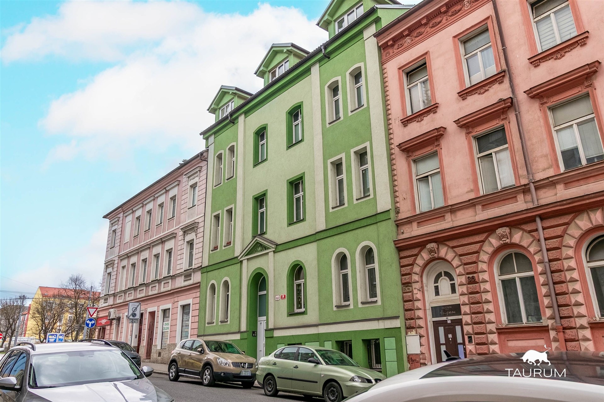 Barevná fasáda činžovního domu, ulice s historickými budovami, zachovalý exteriér, klidná lokalita, blízko centra města.