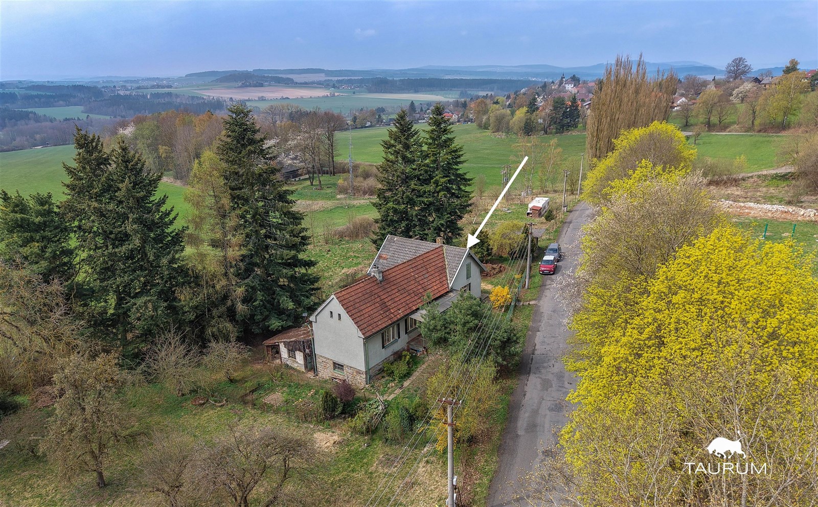 Rodinný dům na venkově, obklopený zelení a stromy, nabízí klidné prostředí. Samostatně stojící budova s šikmou střechou z červených tašek.