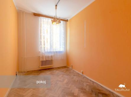 Světlý pokoj s parketovou podlahou, velkým oknem a pastelově vymalovanými stěnami, ideální pro moderní rekonstrukci.