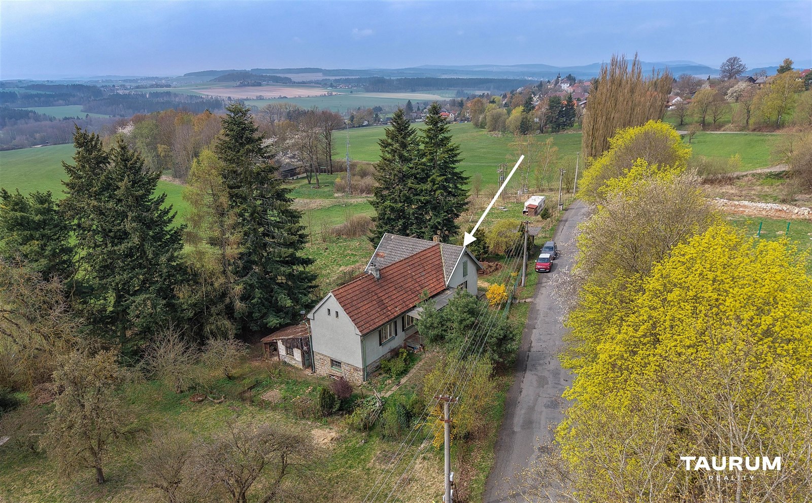 Rodinný dům na venkově, obklopený zelení a stromy, nabízí klidné prostředí. Samostatně stojící budova s šikmou střechou z červených tašek.