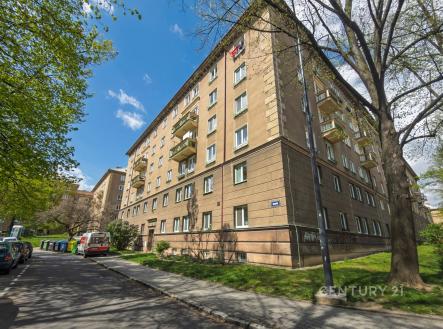 Exteriér bytového domu se zateplenou fasádou, balkony a udržovanými veřejnými prostory, klidná lokalita poblíž centra města.