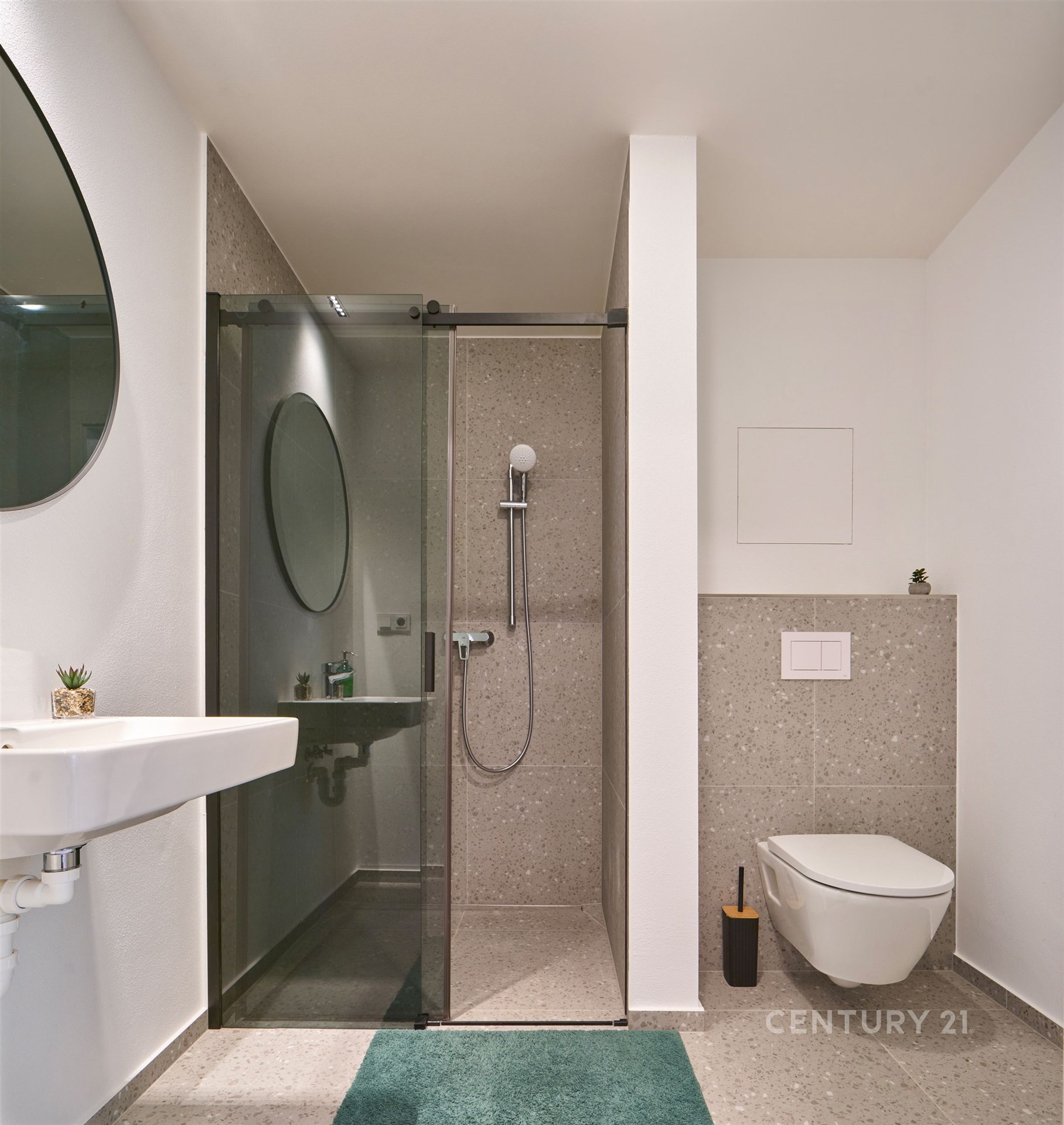 Moderní koupelna s dlažbou, prosklený sprchový kout a minimalistický design, elegantní umyvadlo a závěsné WC pro svěží vzhled.