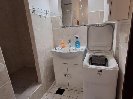 Koupelna s dlažbou, sprchovým koutem a zrcadlem; moderní pračka, bílá sanitární keramika, světlé obklady, prostorný design