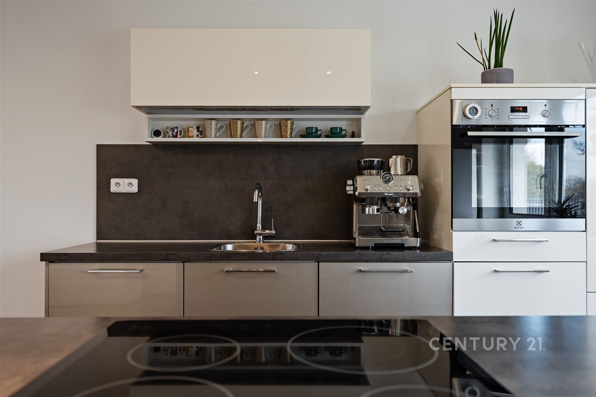 Moderní kuchyň s vestavěnými spotřebiči, tmavou pracovní deskou a lakovanými skříňkami, stylový design a kvalitní materiály.