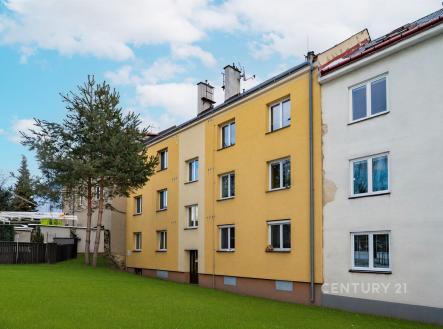 Žlutá fasáda bytového domu se zahradou, moderní okna a rekonstruovaná střecha, klidná lokalita pro rodiny