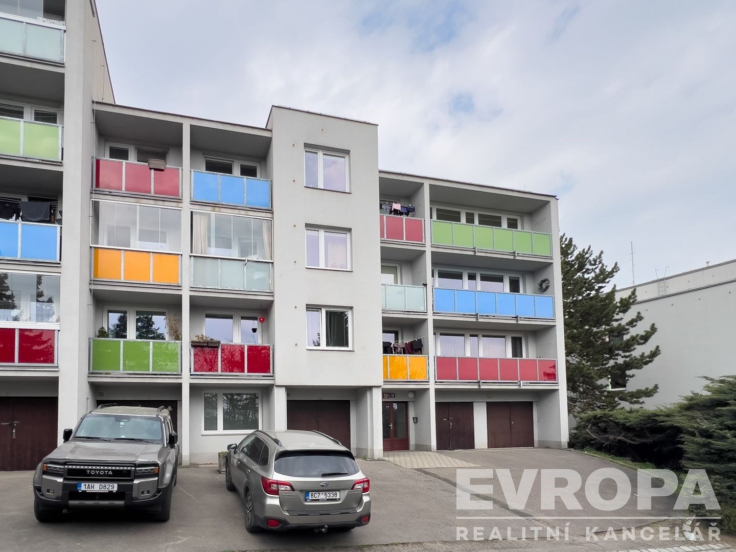 Moderní bytový dům se světlou fasádou, barevnými balkóny a velkými okny nabízí skvělou možnost k investici ve vyhledávané lokalitě.