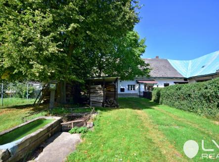 Pohled z přístupové cesty k domu, kamenné koryto s pitnou vodou