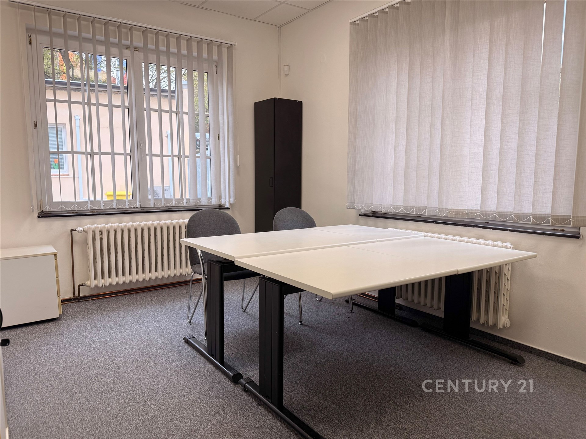 Kancelář s kobercem, velkými okny a moderním vybavením, ideální pro pracovní prostor, světlé stěny, centrální vytápění.