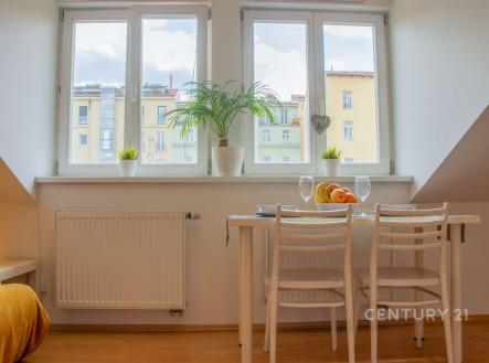 Světlá jídelna, parketová podlaha, velká okna, moderní interiér.