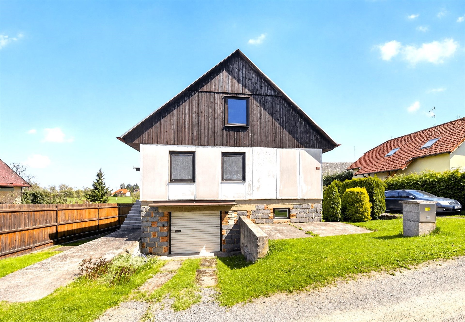 Rodinný dům s moderní dřevěnou fasádou, kamenné detaily, velká zahrada, klidná lokalita.
