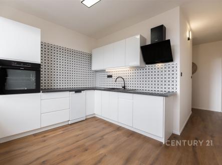 Moderní kuchyň s bílými skříňkami, parketovou podlahou a stylovými dlaždicemi na stěně, poskytující světlý a elegantní prostor