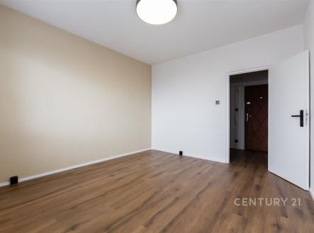 Prázdná místnost s dřevěnou podlahou, světlými stěnami a moderními dveřmi; nový interiér ideální k úpravám.