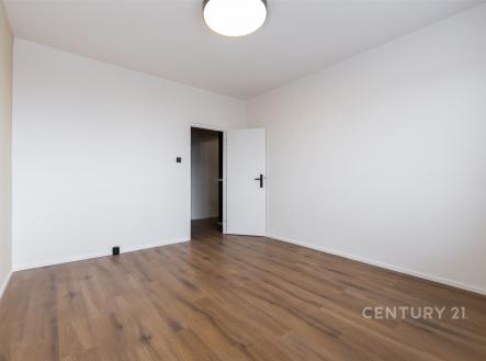 Prázdná ložnice s dřevěnou podlahou, světlé stěny a moderní osvětlení, připravená k úpravě dle vlastního vkusu.