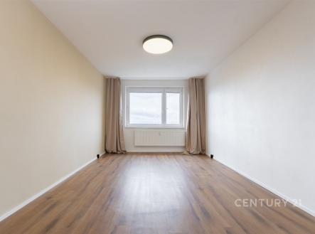 Prostorná ložnice s parketovou podlahou, velké okno poskytující dostatek světla, moderní minimalistický styl interiéru.