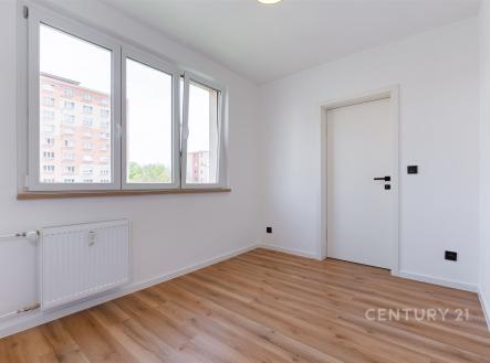 Světlý pokoj s parketovou podlahou a velkými okny, moderní styl, bílá stěna a dveře, ideální pro vytvoření osobního prostoru