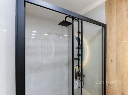 Moderní koupelna s proskleným sprchovým koutem, černými kovovými prvky a dřevěnými obklady, elegantní design a kvalitní materiály