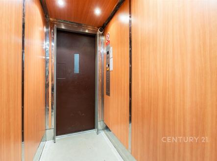 Moderní výtah s dřevěnými panely a nerezovými prvky, nabízí rekonstrukci s pohodlným vstupem do renovovaného domu.