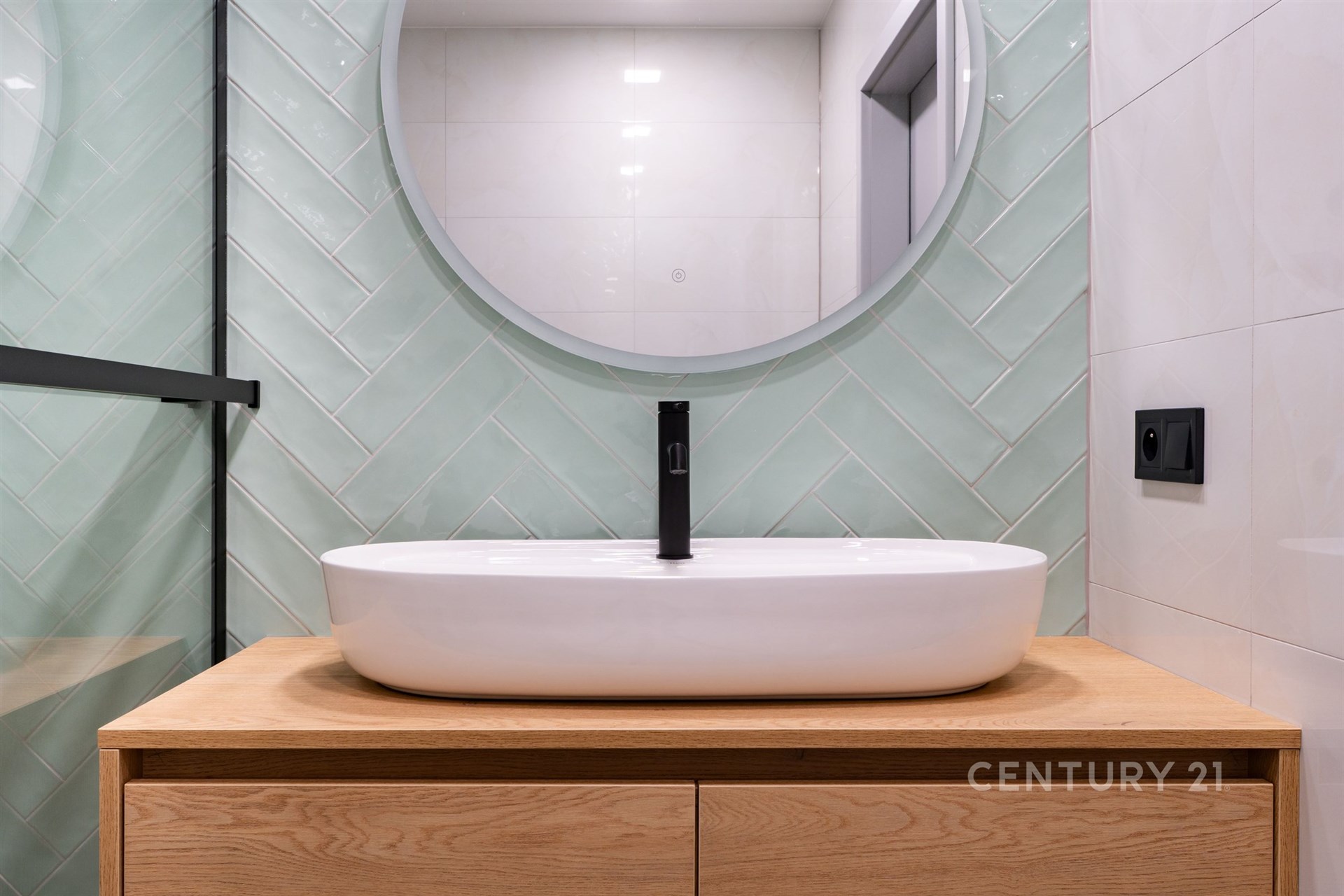 Moderní koupelna s elegantním umyvadlem, dřevěným podstavcem a stylovými obklady zelené barvy, světlý a čistý designový interiér.