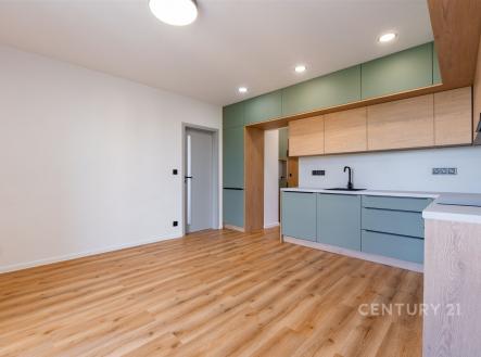 Moderní kuchyň s parketovou podlahou, vestavěné skříně a světlé dřevěné povrchy, minimalistický design a prostorný interiér.