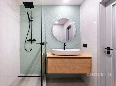 Moderní koupelna s velkou sprchou, dlažbou v rybí kosti a elegantním umyvadlem. Světlý prostor s minimalistickým designem a chladnými tóny.