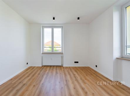 Světlý obývací pokoj s parketovou podlahou má velká okna a moderní osvětlení, ideální pro světlý a vzdušný interiér.