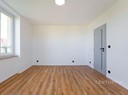 Prázdný pokoj s parketovou podlahou, velkými okny a moderními dveřmi, světlá atmosféra vhodná pro osobní úpravy.