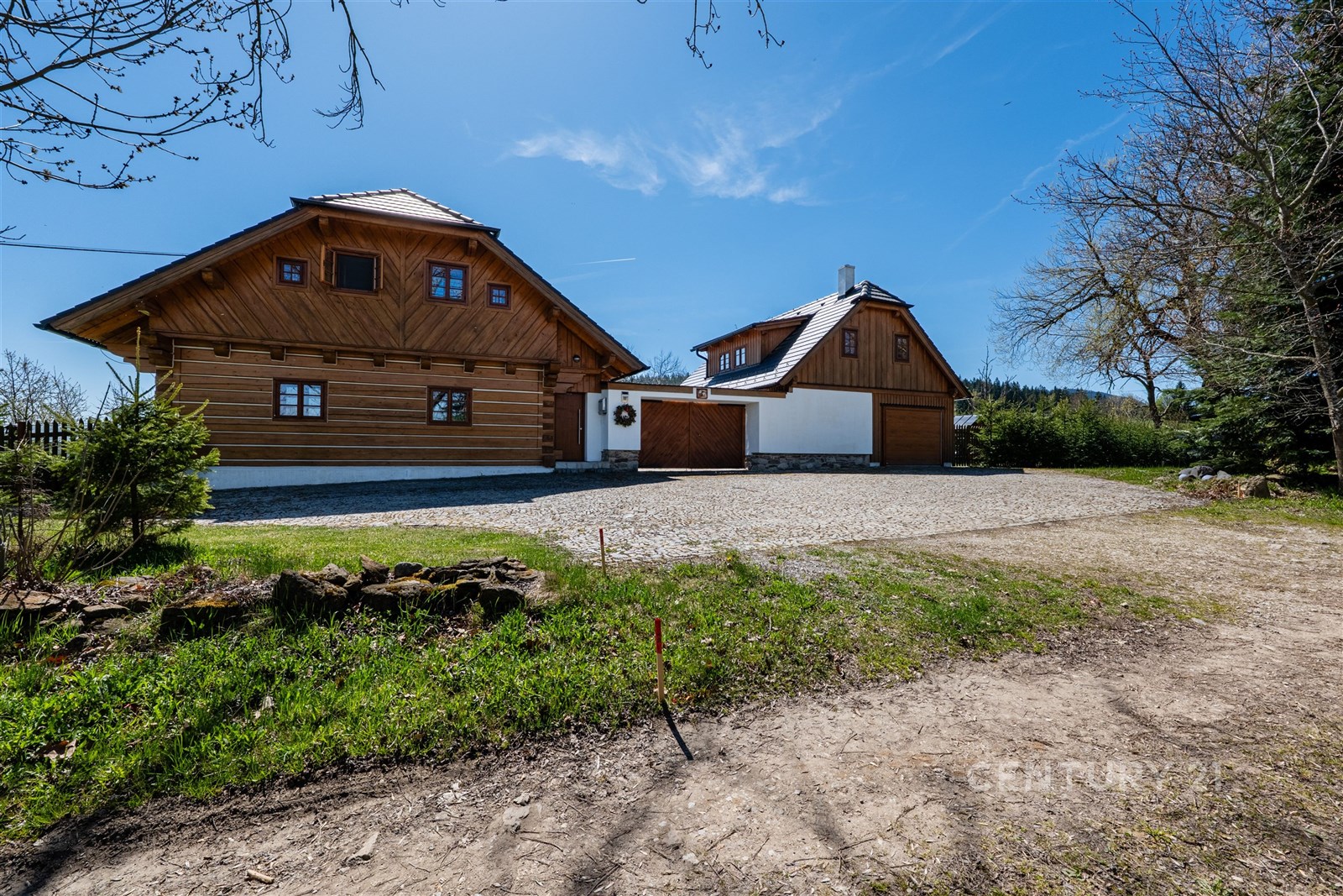 Dřevěná chata s dřevo-fasádou a moderní střechou, umístěná v klidné lokalitě, nabízí prostornou zahradu a garáž pro více vozidel.