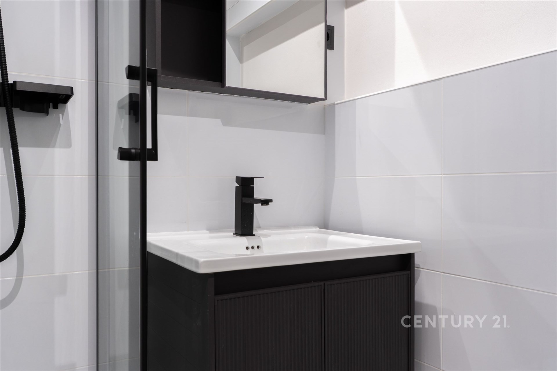 Moderní koupelna s černými doplňky, elegantní dlažbou a kvalitním sprchovým koutem vytváří funkční a stylový prostor.