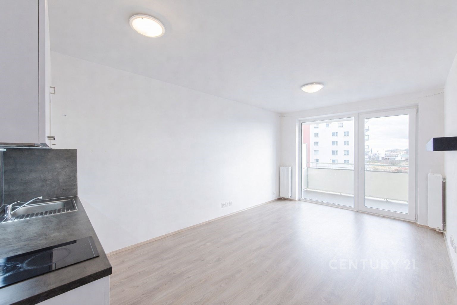 Světlý obývací pokoj s moderní parketovou podlahou, velká okna a světlá výmalba dodávají prostoru vzdušnost a příjemnou atmosféru.