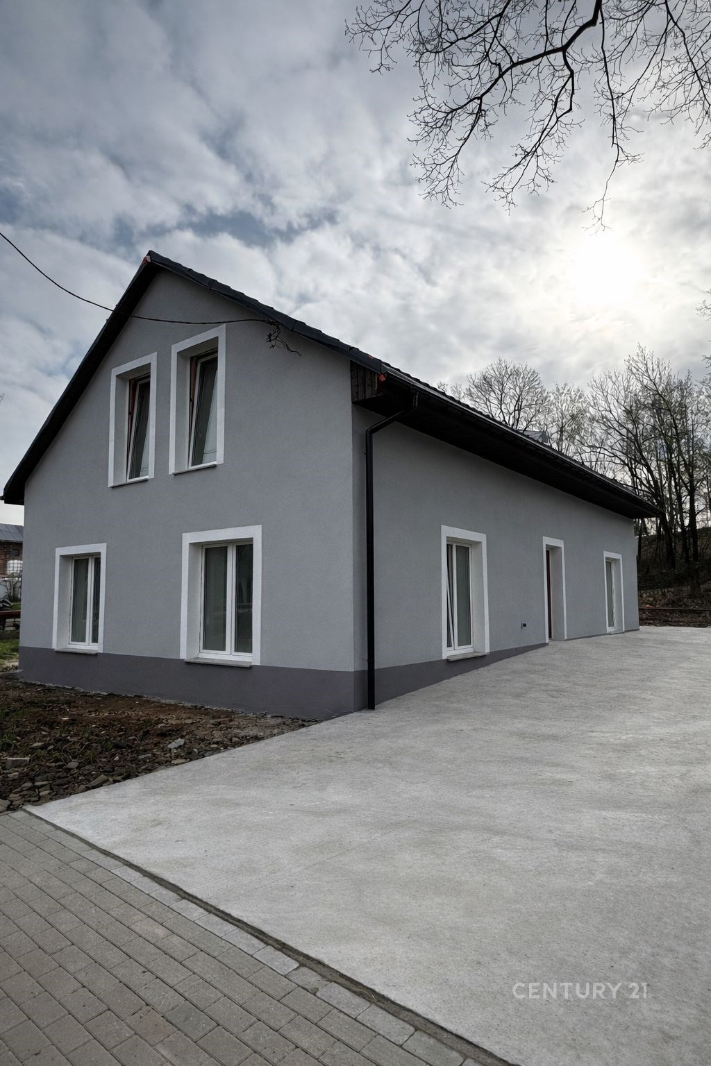 Moderní rodinný dům s šedou omítkou, nová plastová okna a prostorná příjezdová cesta, nacházející se v klidné lokalitě.