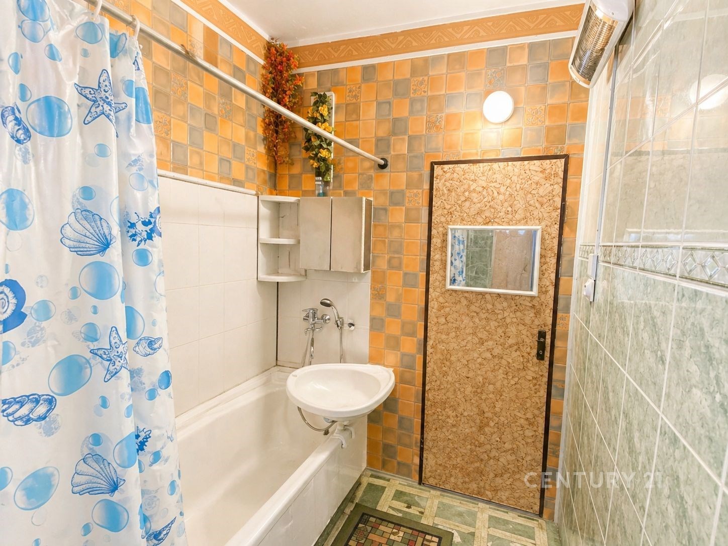 Koupelna se světlými dlaždicemi, vestavěnými úložnými skříněmi a sprchovým koutem. Retro styl a praktické uspořádání prostoru.