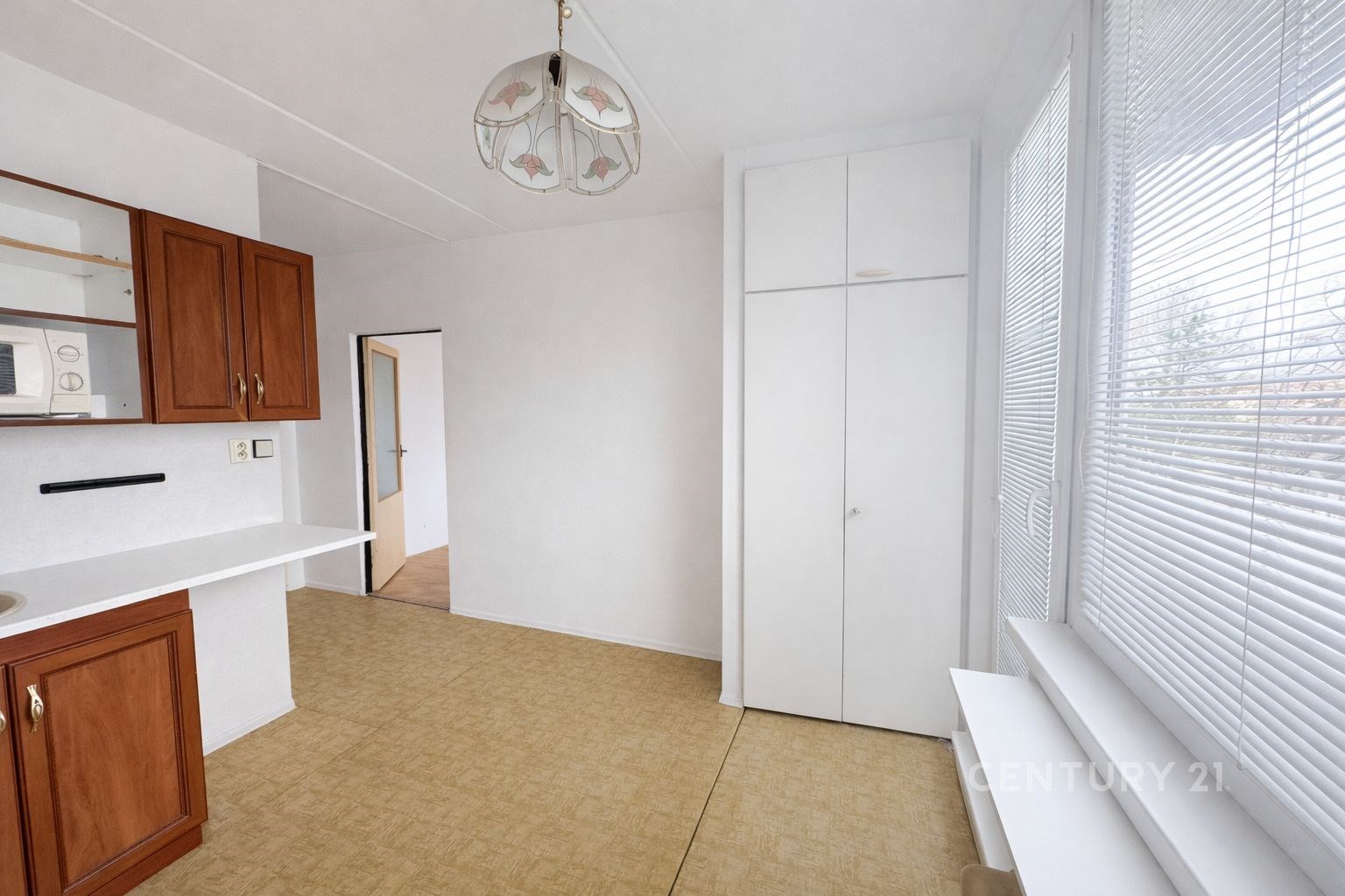 Světlá kuchyň s parketovou podlahou a vestavěnými skříněmi, doplněná velkými okny pro přirozené světlo, v moderním stylu.