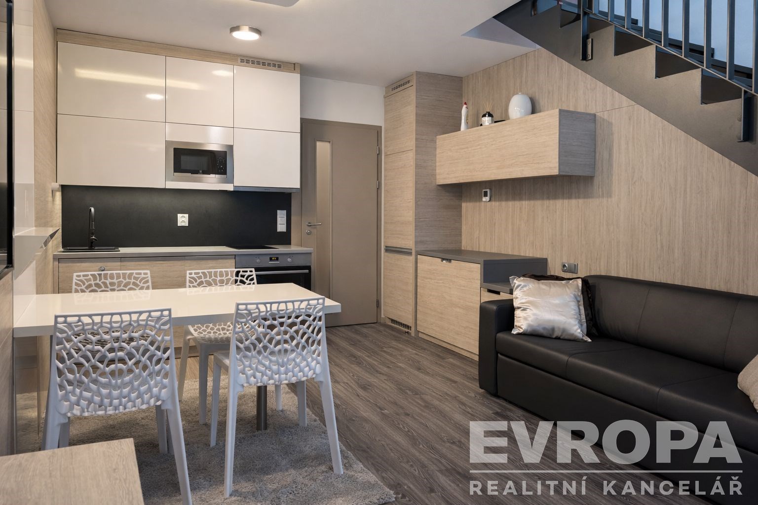 Moderní kuchyň s parketovou podlahou, vestavěné skříně a světlý interiér, útulný obývací prostor pod schody