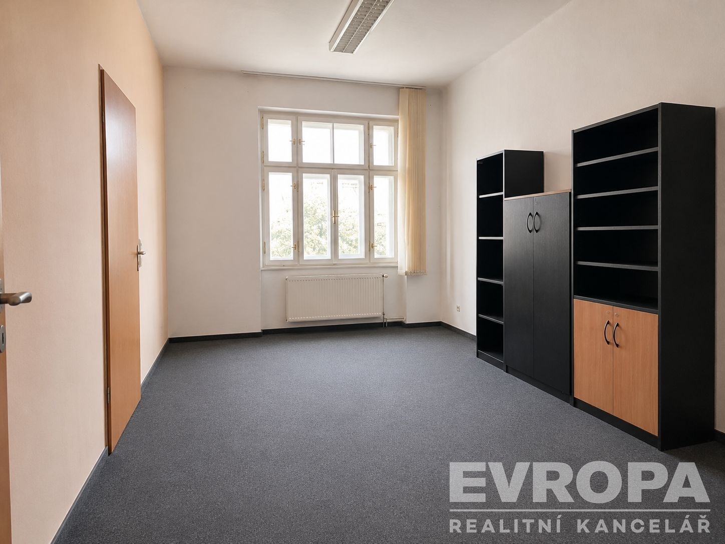 Světlá kancelář s velkými okny, moderní koberce a vestavěné police poskytují praktický prostor pro podnikání.