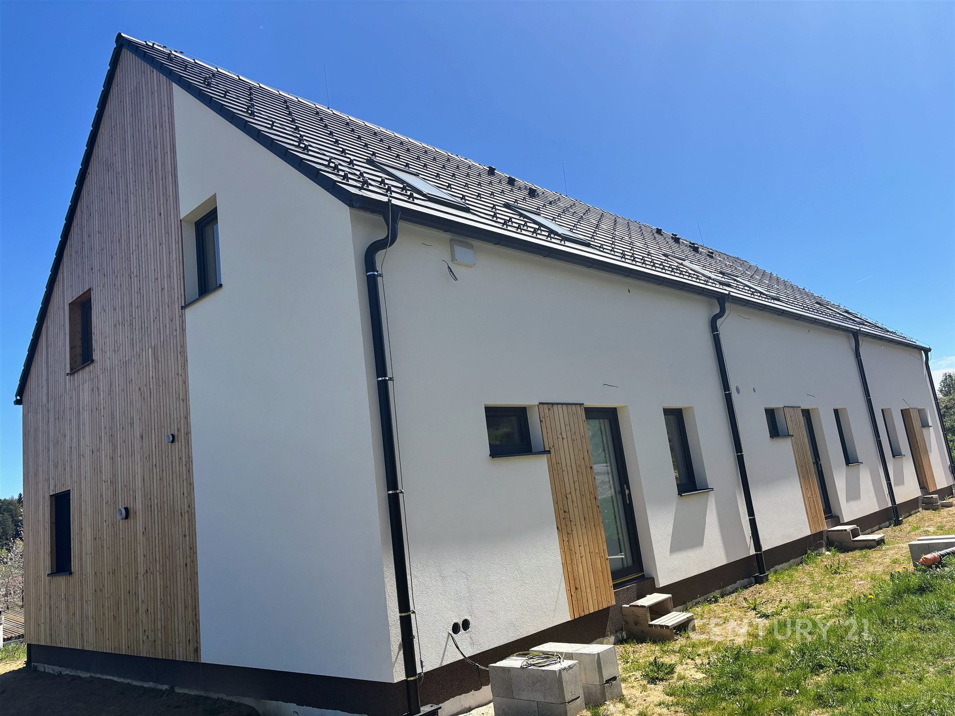 Novostavba se sedlovou střechou kombinuje moderní dřevěné obložení a omítku, nabízí energeticky úsporné bydlení v klidné lokalitě.