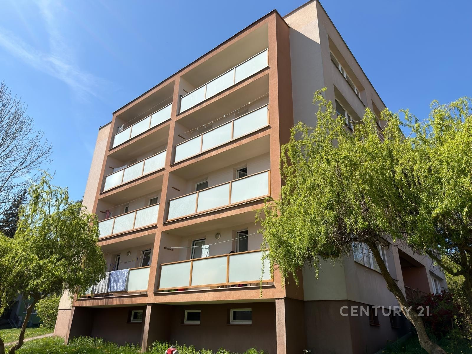 Exteriér bytového domu s moderními balkony a upravenou zelení, ve výborném stavu, nachází se v klidné lokalitě.